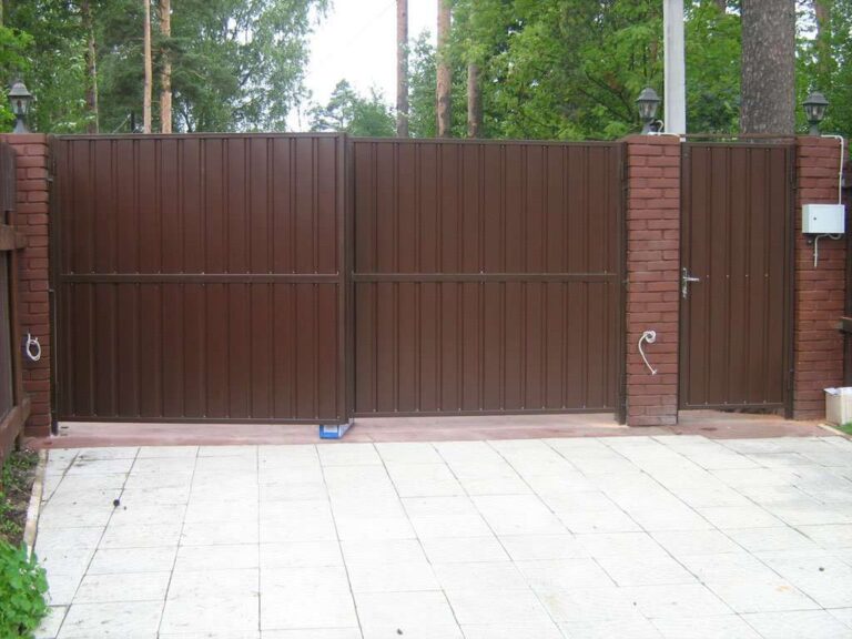 Распашные ворота из профнастила и калитка между кирпичными столбами